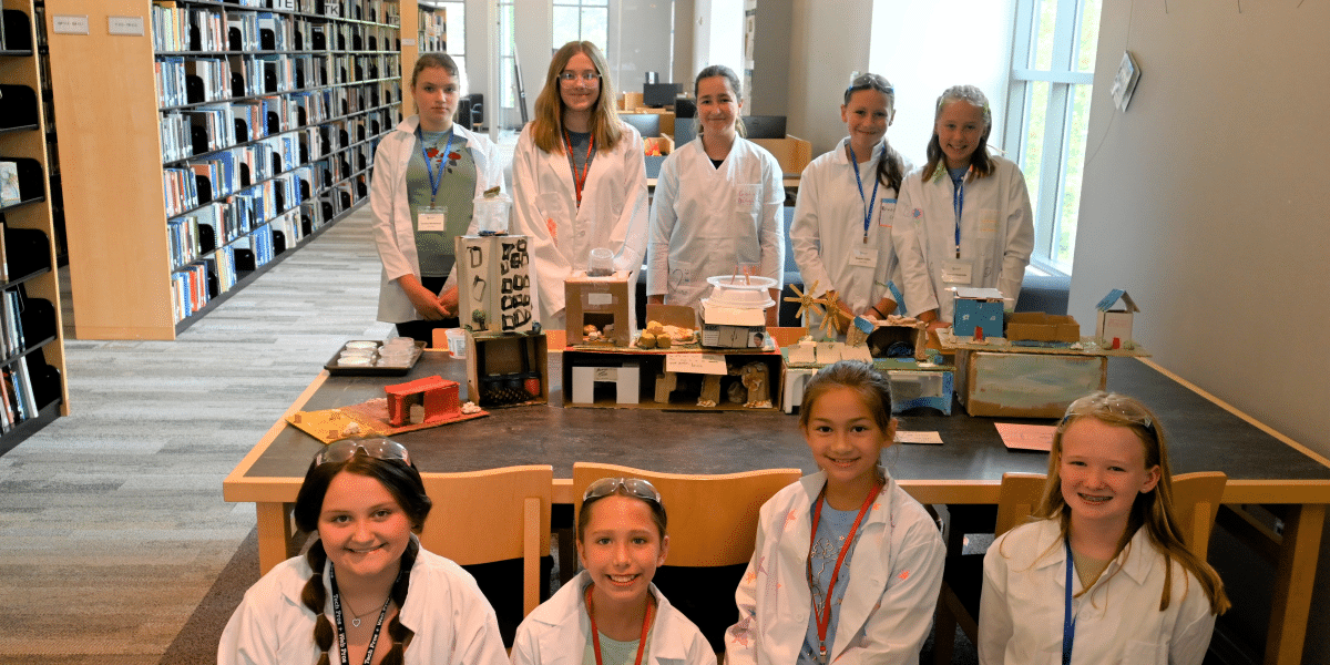 Participants in the WISE Institute smile next to their science project.