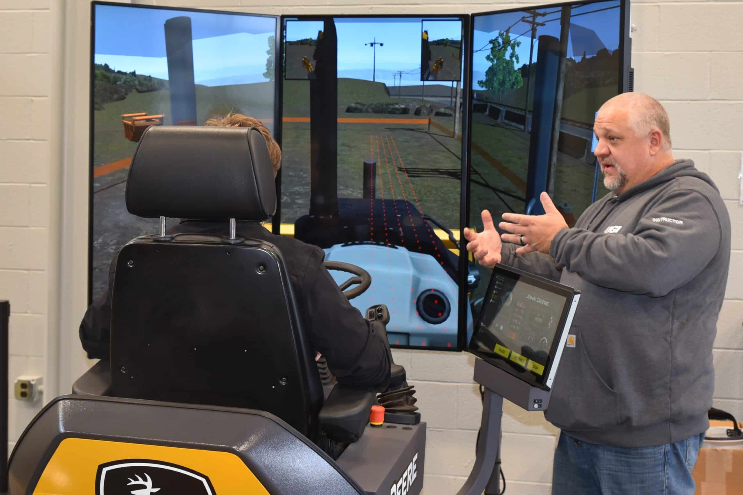 UGI employee teaching student about UGI's use of the driving simulator student is sitting on which is used to train UGI construction employees