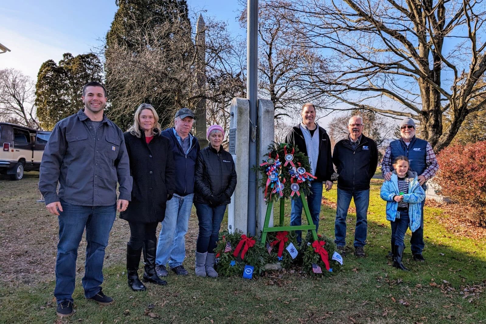 UGI employees and family posing for picture by veteran grave with wreath and ribbons