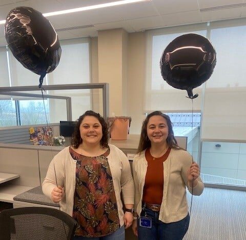 Two UGI employees hold black balloons at their cubicles in support of overdose awareness.