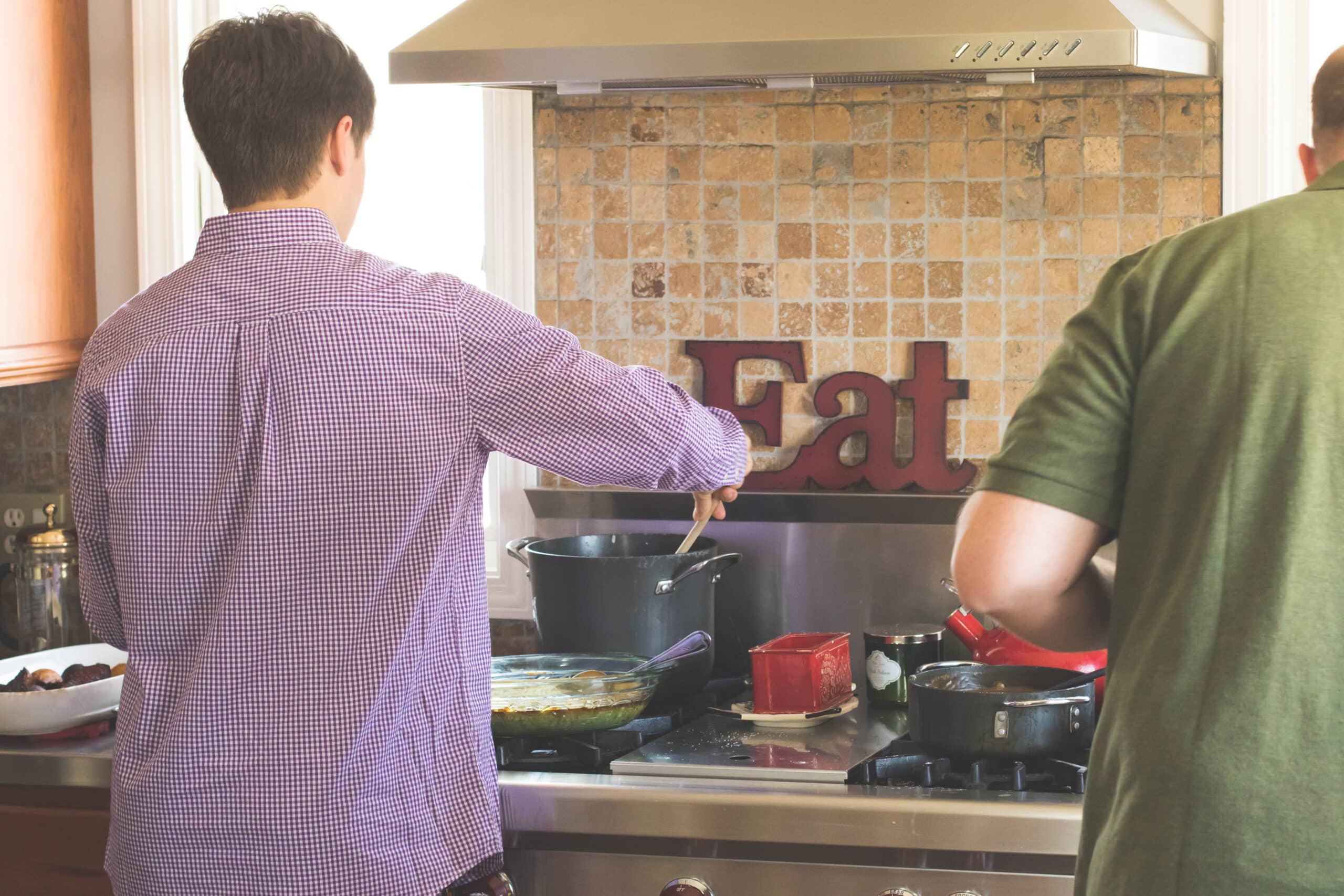 Two people cook on the stove