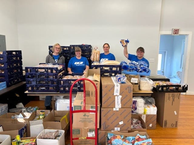 UGI volunteers stand with boxes of food.