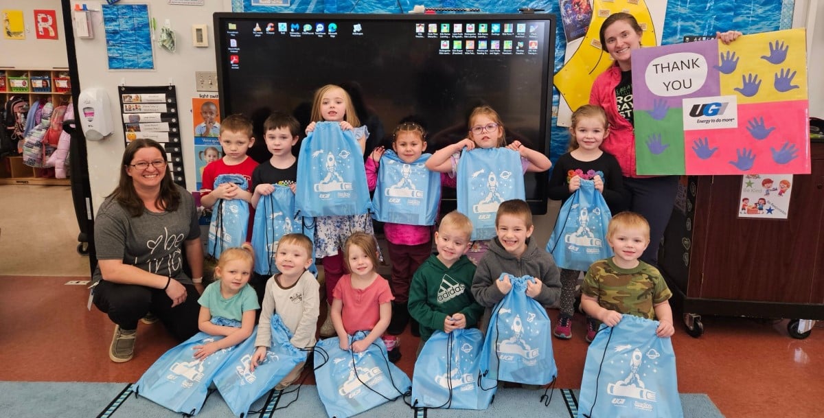 Students and teachers smile with literacy kits.