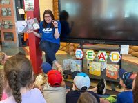 A UGI employee reading a book to young children.